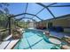 Inviting in-ground screened pool featuring a rock waterfall, sun shelf with table and ample deck space at 1406 Woodcrest, North Port, FL 34286