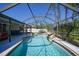Gorgeous in-ground screened pool with a rock waterfall, tanning ledge, and ample lounging space at 1406 Woodcrest, North Port, FL 34286