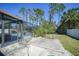 Back patio area with a screened pool enclosure, lush greenery, and concrete patio at 1406 Woodcrest, North Port, FL 34286