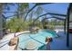 In-ground screened pool with a rock waterfall feature and mature landscaping at 1406 Woodcrest, North Port, FL 34286