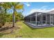 Backyard features a screened-in pool and patio area, surrounded by lush lawn and palm trees at 1508 Westover St, Port Charlotte, FL 33953