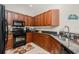 Efficient kitchen featuring dark wood cabinetry, black appliances, and ample counter space for meal preparation at 17200 Acapulco Rd # 123, Punta Gorda, FL 33955