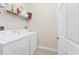 Well-lit laundry room with a modern white washer and dryer, shelving, and tile floor at 17200 Acapulco Rd # 123, Punta Gorda, FL 33955