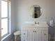 Bathroom featuring a single sink vanity, a round mirror, and a window for natural light at 22191 New Rochelle Ave, Port Charlotte, FL 33952