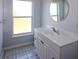 Bathroom featuring a single sink vanity, a round mirror, and a window for natural light at 22191 New Rochelle Ave, Port Charlotte, FL 33952