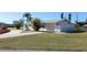 A single-story home with white exterior, a driveway, and well-kept lawn on a sunny day at 22191 New Rochelle Ave, Port Charlotte, FL 33952