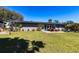 Large backyard with green grass, patio, outdoor seating, and mature trees at 23179 Maclellan Ave, Port Charlotte, FL 33980