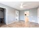A bedroom with a ceiling fan, tile floor, three doorways, and gray walls at 23179 Maclellan Ave, Port Charlotte, FL 33980