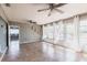 Large living room featuring tile floors, multiple windows, and a ceiling fan with access to the backyard at 23179 Maclellan Ave, Port Charlotte, FL 33980