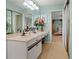 Bright bathroom with double sinks, flower arrangements, tile flooring, and access to bedroom at 238 Southampton Dr # 319, Venice, FL 34293