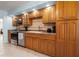 Cozy kitchen featuring wooden cabinetry, tile backsplash, stainless steel appliances, and tile flooring at 238 Southampton Dr # 319, Venice, FL 34293