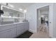 Modern bathroom featuring double sinks, sleek gray cabinets, and a large, illuminated mirror at 25543 Prada Dr, Punta Gorda, FL 33955