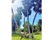 Lush backyard featuring beautiful palm trees and a rustic stone bench, perfect for relaxing at 2715 Taylor Rd, Punta Gorda, FL 33950