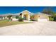 A single-story home showing a two car garage, yellow exterior, and a well manicured lawn at 27394 Natal Dr, Punta Gorda, FL 33983