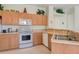 A kitchen view highlighting appliances, sink, wood cabinets, tile floors and a breakfast bar at 2877 Woodward Ave, North Port, FL 34286