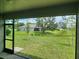 View from screened lanai to grassy backyard with mature trees and landscaping at 354 Porto Alegre St, Punta Gorda, FL 33983