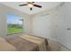 Bedroom featuring a ceiling fan, a large window overlooking the green backyard, and a closet with sliding doors at 481 Starborn St, Port Charlotte, FL 33954