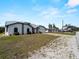 Home exterior with a two-car garage, metal roof, and spacious front yard at 908 Tropical Nw Cir, Port Charlotte, FL 33948