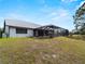 View of home's back exterior with a metal roof, screened in lanai, and large backyard at 908 Tropical Nw Cir, Port Charlotte, FL 33948