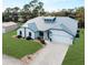 Beautiful single-story home featuring a well-manicured lawn, metal roof, arched entryway, and attached two-car garage at 908 Tropical Nw Cir, Port Charlotte, FL 33948