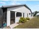 Side exterior view of the home featuring a screened lanai and lush landscaping at 908 Tropical Nw Cir, Port Charlotte, FL 33948