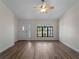 Bright living room with wood-look floors, ceiling fan, and a front door flanked by three windows at 908 Tropical Nw Cir, Port Charlotte, FL 33948