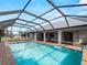 Large screened in pool with brick surround and view of backyard at 908 Tropical Nw Cir, Port Charlotte, FL 33948