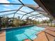 Sparkling pool with screened enclosure, brick patio, and scenic waterfront views at 908 Tropical Nw Cir, Port Charlotte, FL 33948