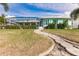 Exterior of home featuring a beautiful lawn and screened-in lanai with walkway to front door at 103 Colony Point Dr, Punta Gorda, FL 33950