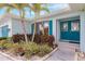 Charming home featuring a vibrant blue front door, lush landscaping, and a welcoming entrance, complemented by tropical palm trees at 103 Colony Point Dr, Punta Gorda, FL 33950