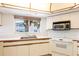 Bright kitchen with white cabinets, stainless steel sink, and modern appliances under a window with tropical view at 11000 Placida Rd # 1501, Placida, FL 33946