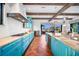 Spacious kitchen featuring custom blue cabinetry, beam ceilings, and terra cotta floors at 1111 San Mateo Dr, Punta Gorda, FL 33950