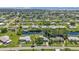 Aerial view showcases a community with waterfront access, lush greenery, and well-maintained homes under a bright sky at 131 Buckeye Nw Ave, Port Charlotte, FL 33952