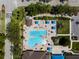 Aerial view of a beautiful community pool featuring blue umbrellas, lounge chairs, and lush landscaping at 13352 Creekside Ln, Port Charlotte, FL 33953