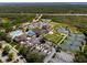 Aerial view of a vibrant community featuring a pool, tennis courts, clubhouse, parking, and lush landscaping at 13352 Creekside Ln, Port Charlotte, FL 33953