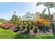 Entrance to Riverwood, a gated community, showcasing colorful landscaping and an American flag at 13352 Creekside Ln, Port Charlotte, FL 33953