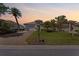Charming home at dusk with a well-kept lawn, brick driveway, and mature palm trees at 13352 Creekside Ln, Port Charlotte, FL 33953