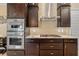 Close-up of stainless steel oven and gas range with dark wood cabinetry and granite countertops at 1341 Pine Siskin Dr, Punta Gorda, FL 33950