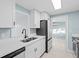 Updated kitchen with white cabinets, stone countertops, stainless steel appliances, and a view to the next room at 146 Francis Ne Dr, Port Charlotte, FL 33952