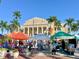 Vibrant outdoor market with stalls and vendors, set against a backdrop of palm trees and a classic building at 17094 Acapulco Rd # 312, Punta Gorda, FL 33955
