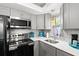 Updated kitchen features gray cabinetry, quartz countertops, stainless steel appliances, and a mosaic backsplash at 19505 Quesada Ave # F103, Port Charlotte, FL 33948