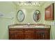 A bathroom showcases a granite countertop double sink vanity and two large oval mirrors at 220 Coldeway Dr # 211, Punta Gorda, FL 33950