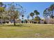Expansive green lawn with mature trees and distant views of community amenities, creating a serene and inviting outdoor space at 2300 Aaron St # 106, Port Charlotte, FL 33952
