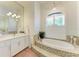 Bright bathroom with tiled tub, white cabinets, and a large mirror at 333 Santander Ct, Punta Gorda, FL 33950
