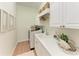 Well-organized laundry room with white cabinets, sink, counter space, shelving, and decor at 333 Santander Ct, Punta Gorda, FL 33950