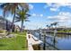Scenic canal view with a private dock, lush landscaping, and neighborhood homes in the background at 3335 Grenada Ct, Punta Gorda, FL 33950