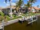 Canal-front property featuring a private boat dock with lift, screened lanai and lush landscaping for the home at 3335 Grenada Ct, Punta Gorda, FL 33950
