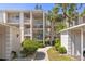 Multi-story condo building featuring white walls, balconies, tropical landscaping, and a pathway leading to the entrance at 437 Cerromar Ln # 418, Venice, FL 34293