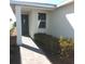 Home exterior view with covered entrance, manicured shrubs, brick paver walkway and gray front door at 43735 Cattleman Dr, Punta Gorda, FL 33982