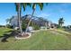 Well-maintained backyard with a screened-in pool, grassy area, and lush tropical landscaping at 609 Macedonia Dr, Punta Gorda, FL 33950